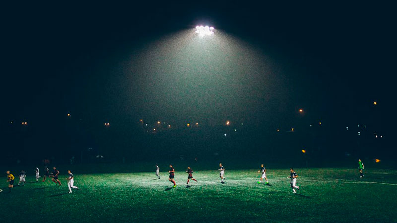 Grupo de pessoas jogando futebol no escuro